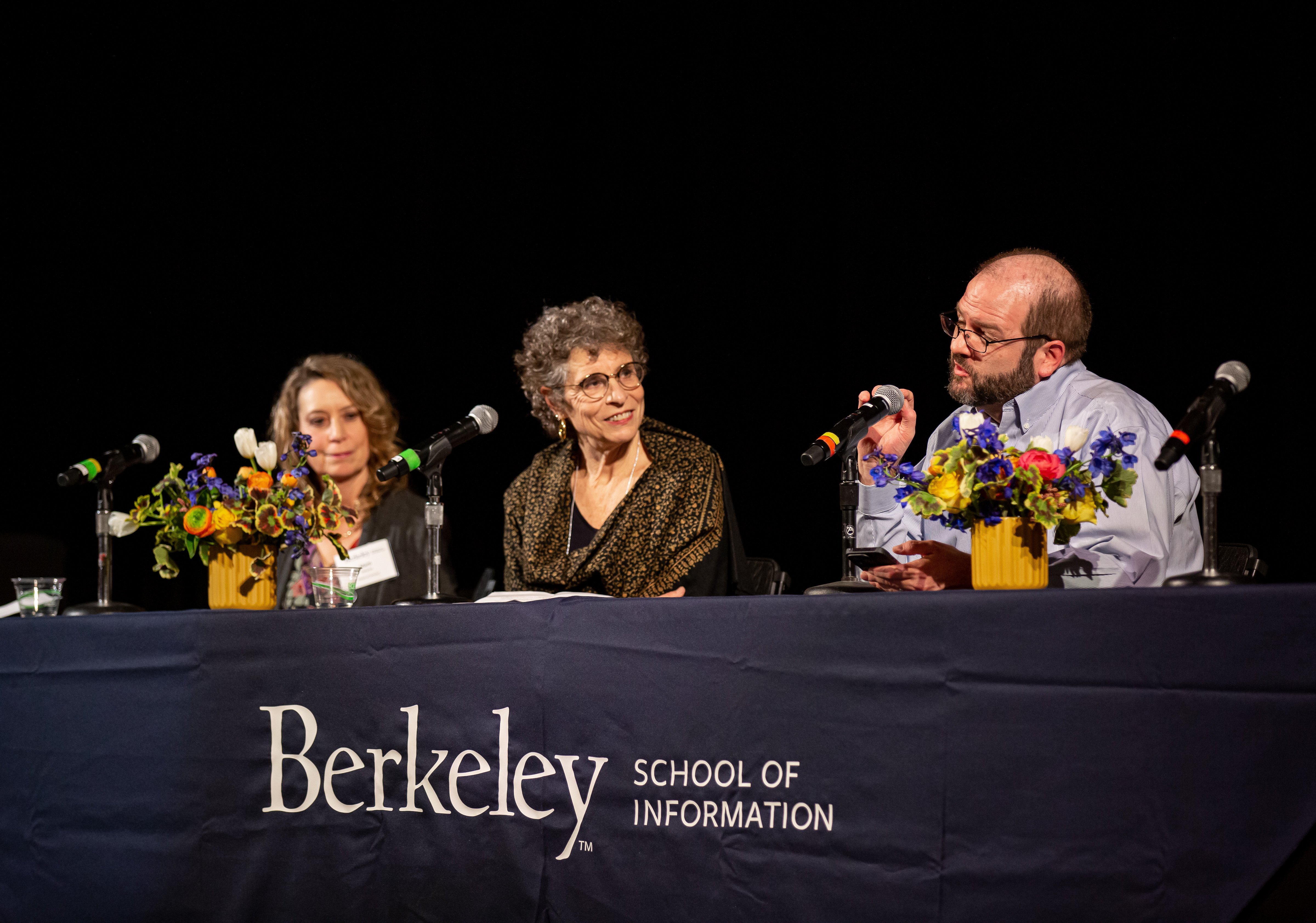 three people discussing at a table for a panel