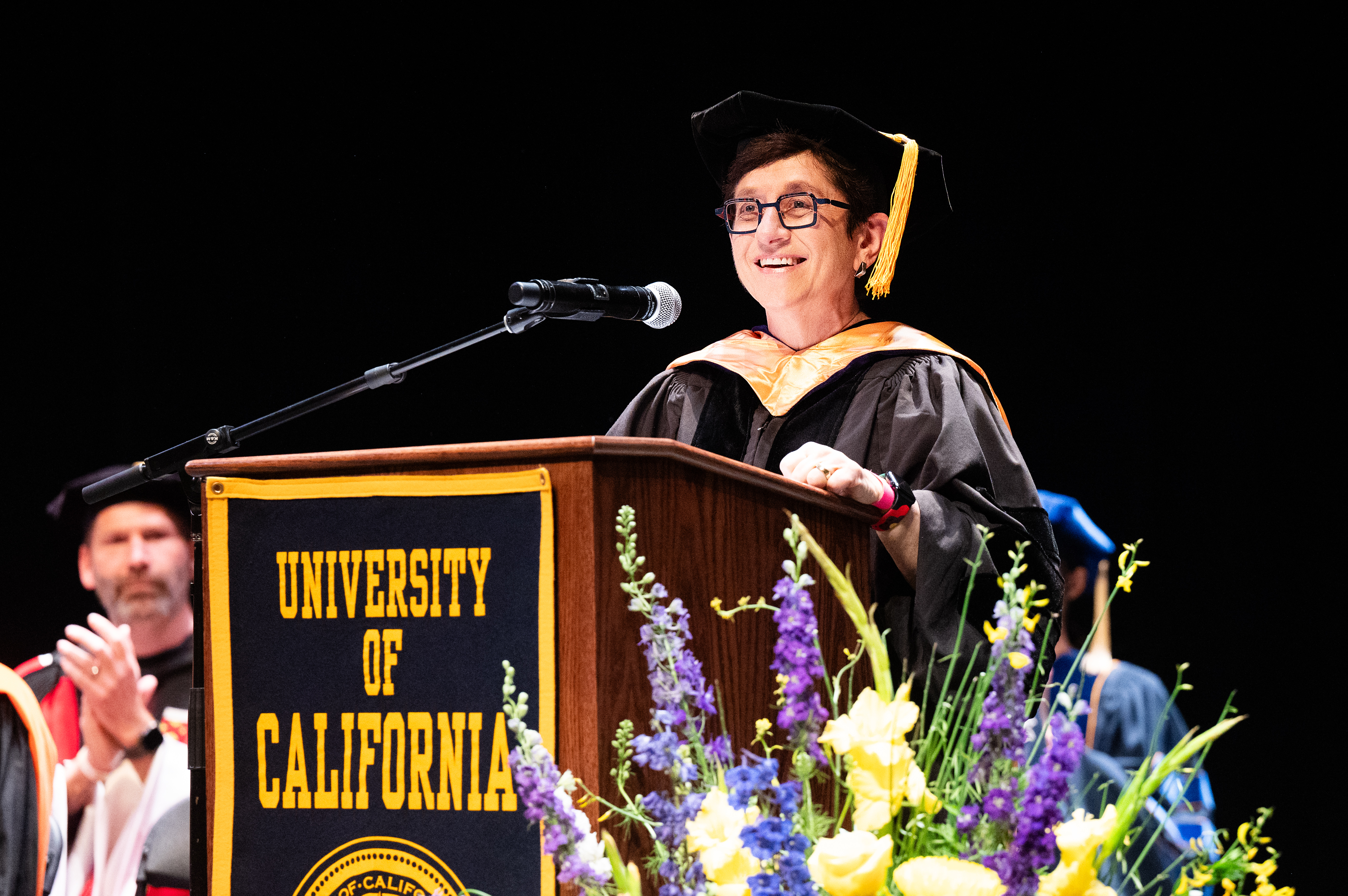 woman in glasses and regalia at lectern