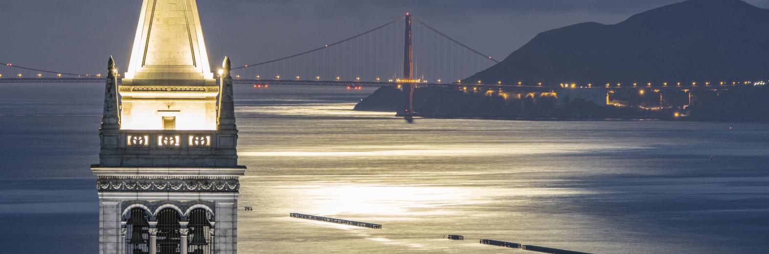 Photo of the Golden Gate Bridge at night, with Berkeley's campanile in the foreground