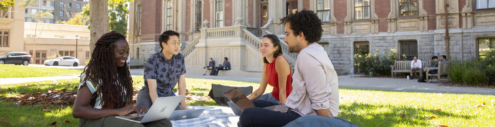 Several students studying together, sitting on the grass in front of South Hall
