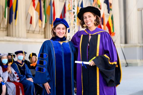 image of two women in doctoral regalia, smiling for the camera.