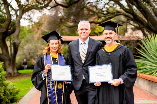 two grads pose with a professor