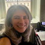Prof. Deirdre Mulligan smiles in front of a window in her office in Washington DC