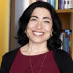 Photo of Jennifer Chayes smiling with bookshelves in the background