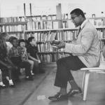James Henry Jacobs Jr. playing guitar to audience of kids at library