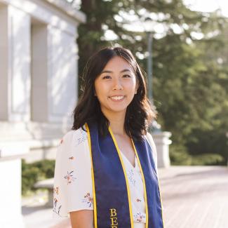photo of Helen Li standing in front of Wheeler Hall at UC Berkeley wearing a graduation sash