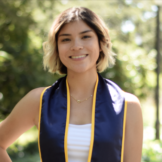 A women with short blonde hair wearing white and a UC Berkeley stole.