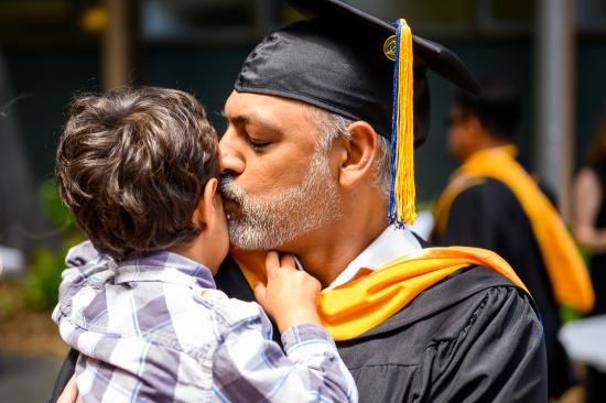 graduating parent kisses child's cheek