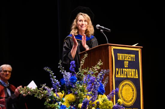 photo of Marti Hearst in graduation regalia standing at a podium, smiling