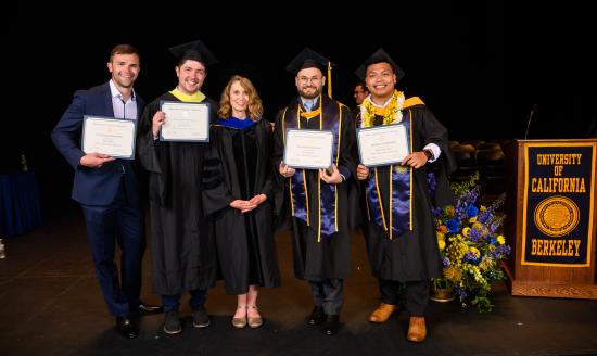 four men pose with a woman in graduation regalia
