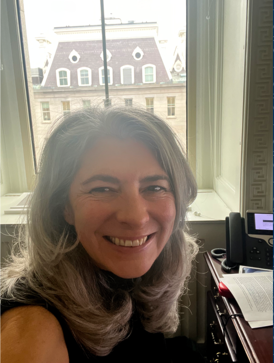Prof. Deirdre Mulligan smiles in front of a window in her office in Washington DC