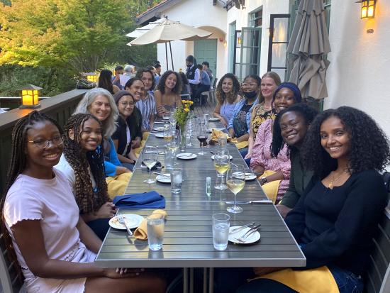 group of students, faculty, and staff at an outdoor dinner table