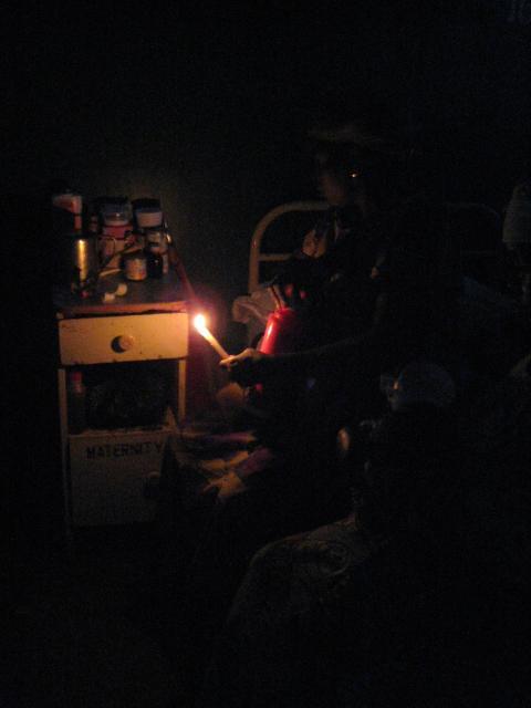 A patient in a Nigerian maternity ward holds a candle as her only source of light.