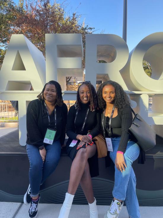 three women sitting in front of afrotech sign