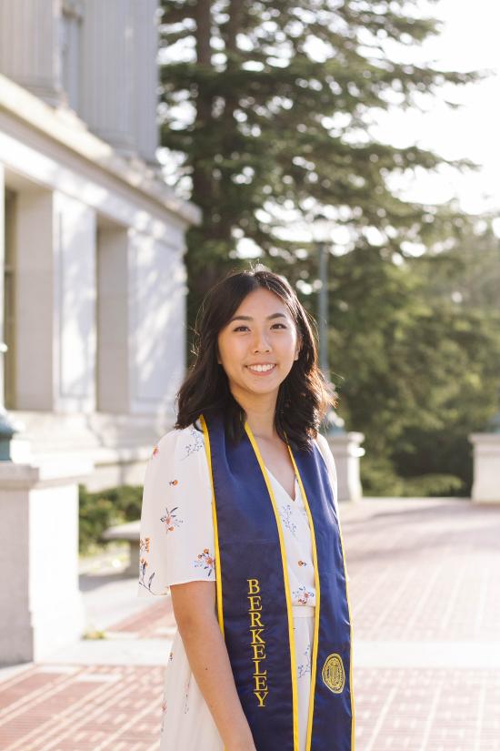 photo of Helen Li standing in front of Wheeler Hall at UC Berkeley wearing a graduation sash